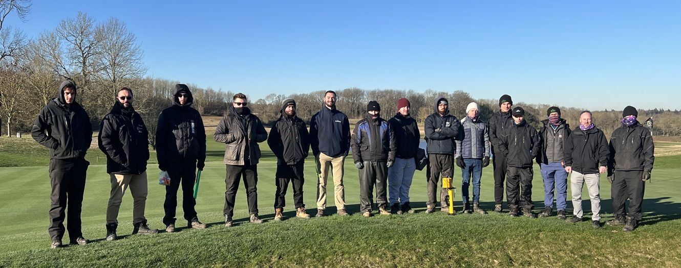 A number of young students stood in front of bunker on golf course