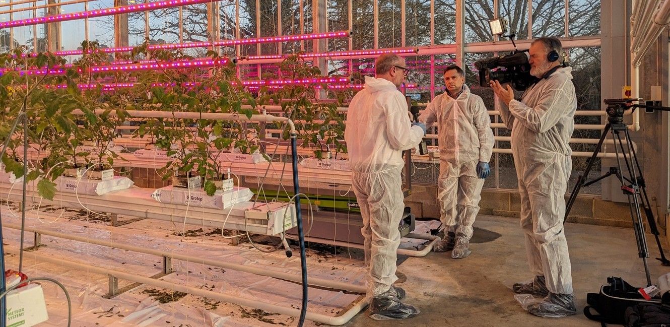 Camera man and presenter in greenhouse