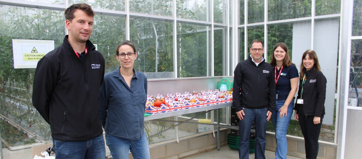 Five people surrounding counter with tomatoes on