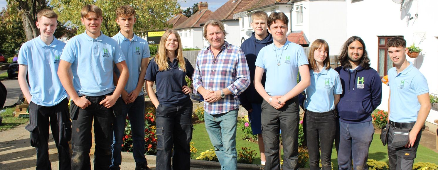 Group of students in front garden of house with David Domoney