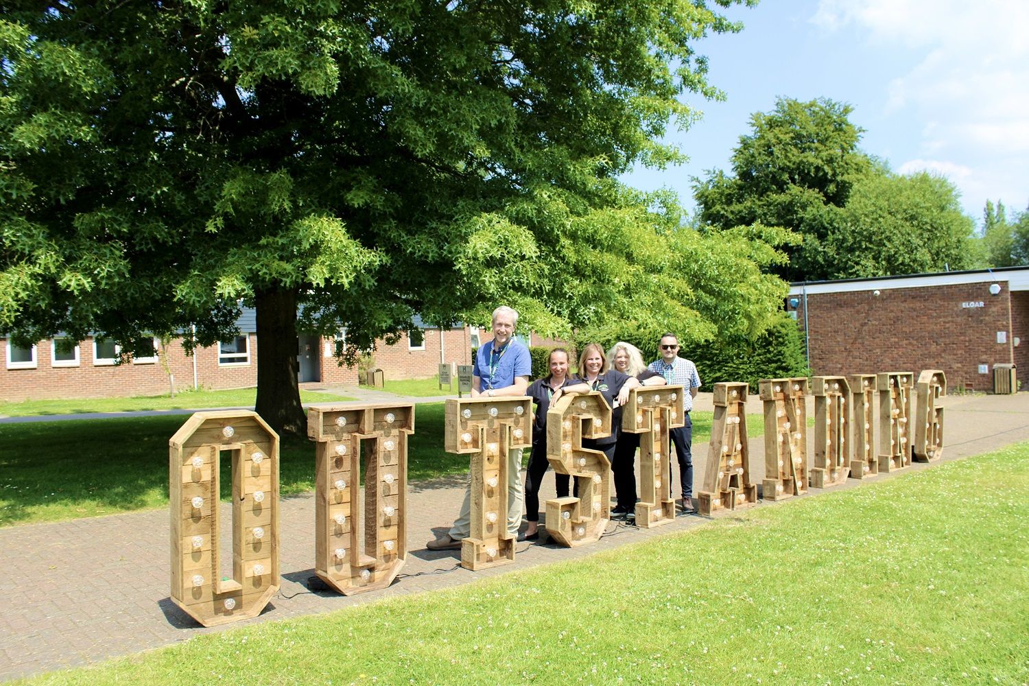 Staff standing behind Outstanding letters